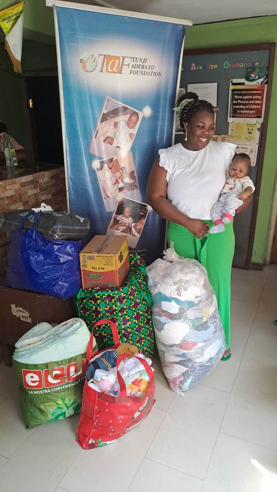 Una referente di un orfanotrofio in Nigeria accanto ai sacchi di vestiti e materiali ricevuti