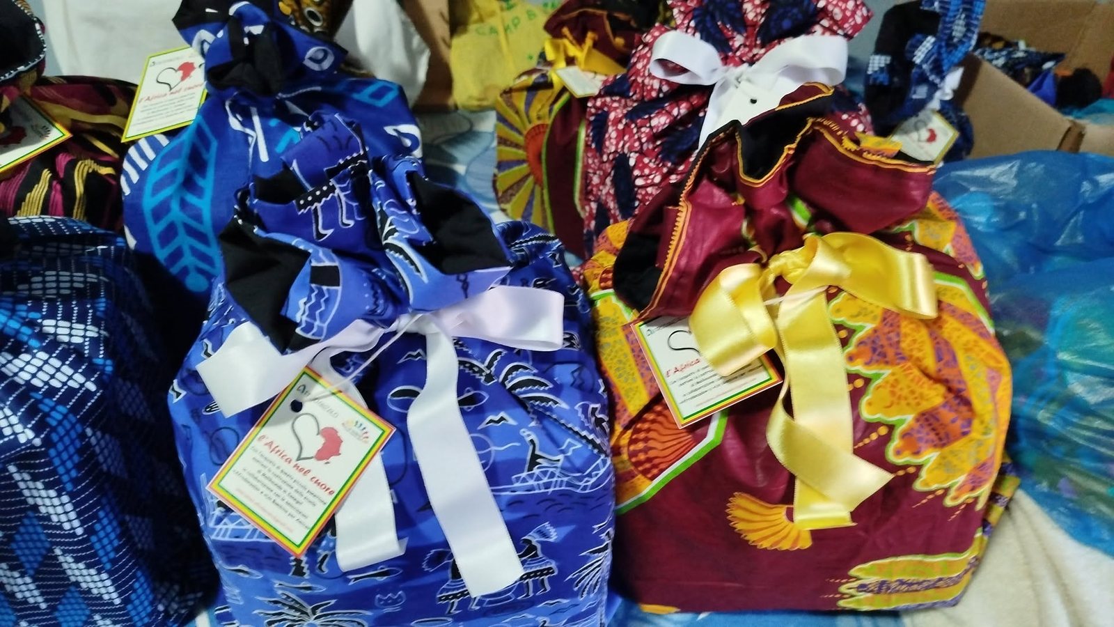 Panettoni solidali confezionati dentro shopping bag di tessuto africano con fiocchi colorati e cartellini