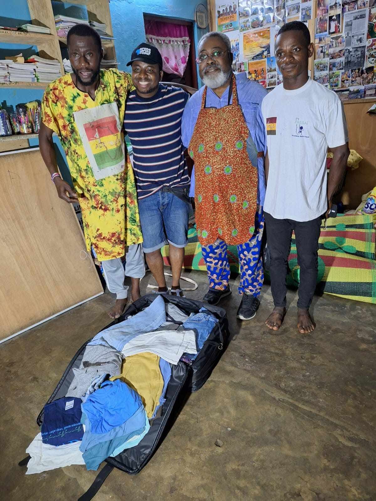 Quattro persone in Togo accanto a una valigia aperta con i vestiti arrivati dal Bazar Ubuntu