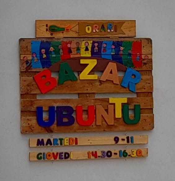 L'insegna in legno colorato del Bazar Ubuntu, con gli orari di apertura: martedì 9-11, giovedì 14.30-16.30