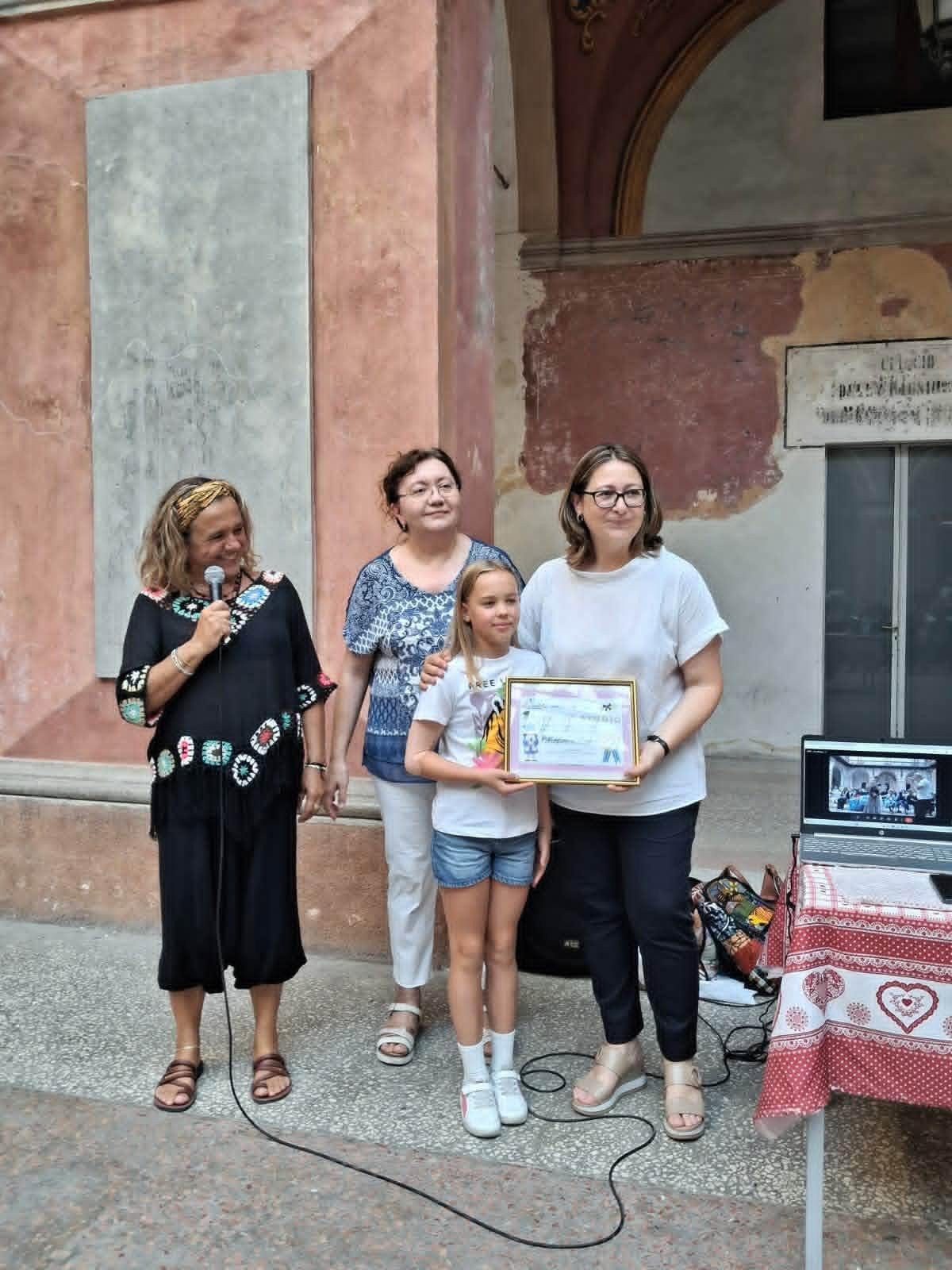 Una delle premiate riceve la borsa di studio insieme a due volontarie dell'associazione