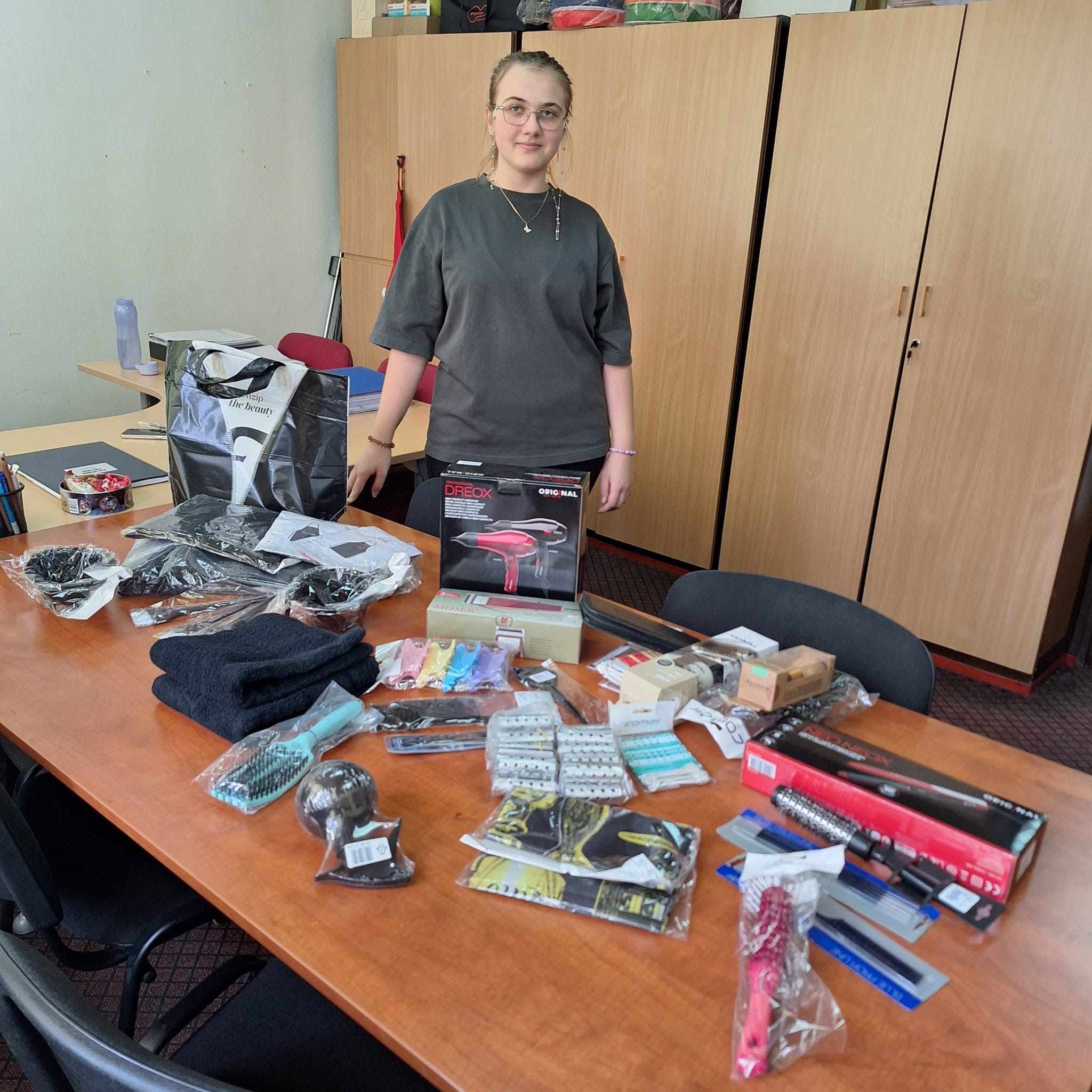 Una beneficiaria della borsa di studio con strumenti e prodotti acquistati per la scuola di parrucchiera