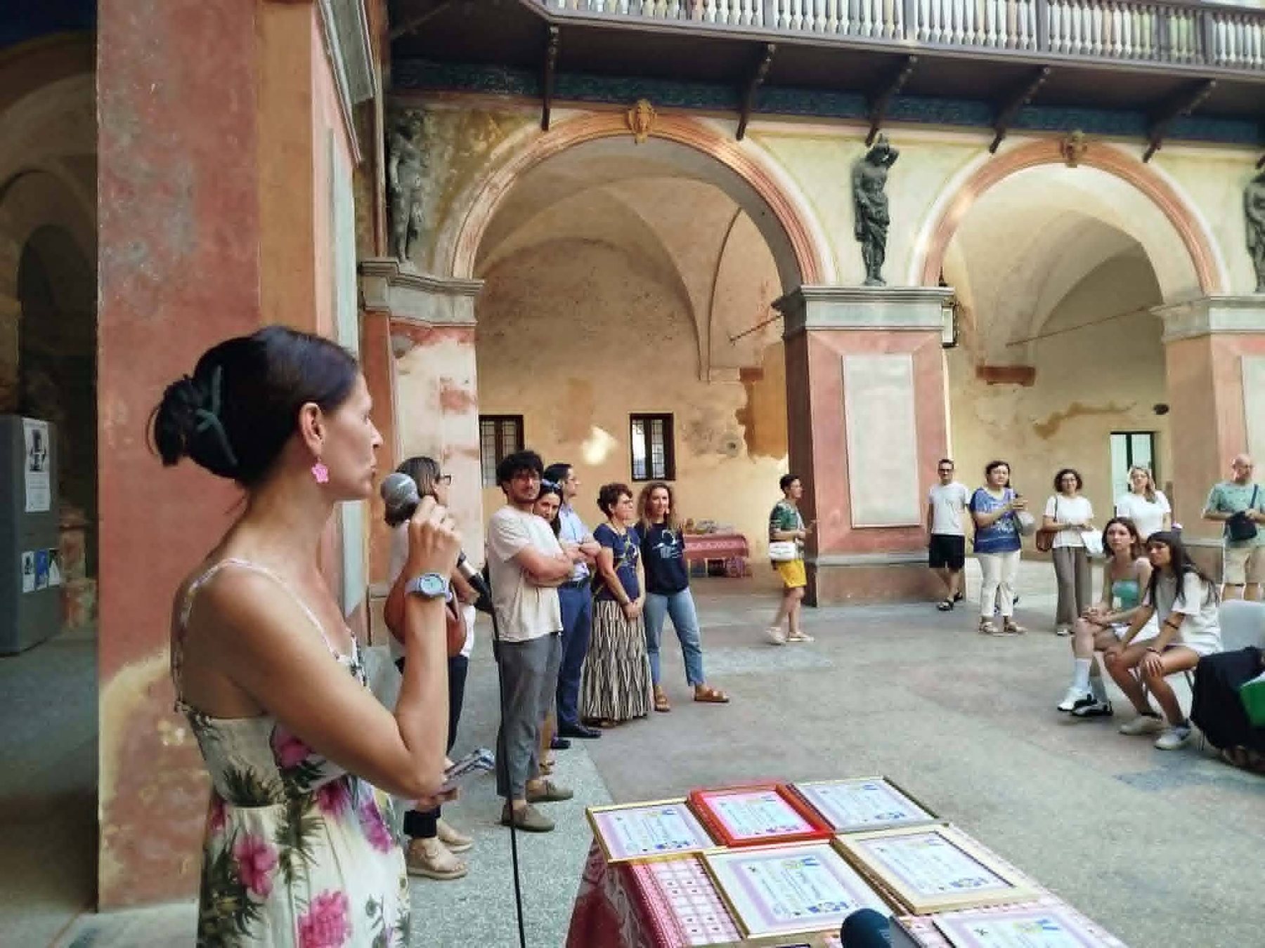 La cerimonia delle borse di studio nel chiostro: le sette pergamene incorniciate sul tavolo e il pubblico