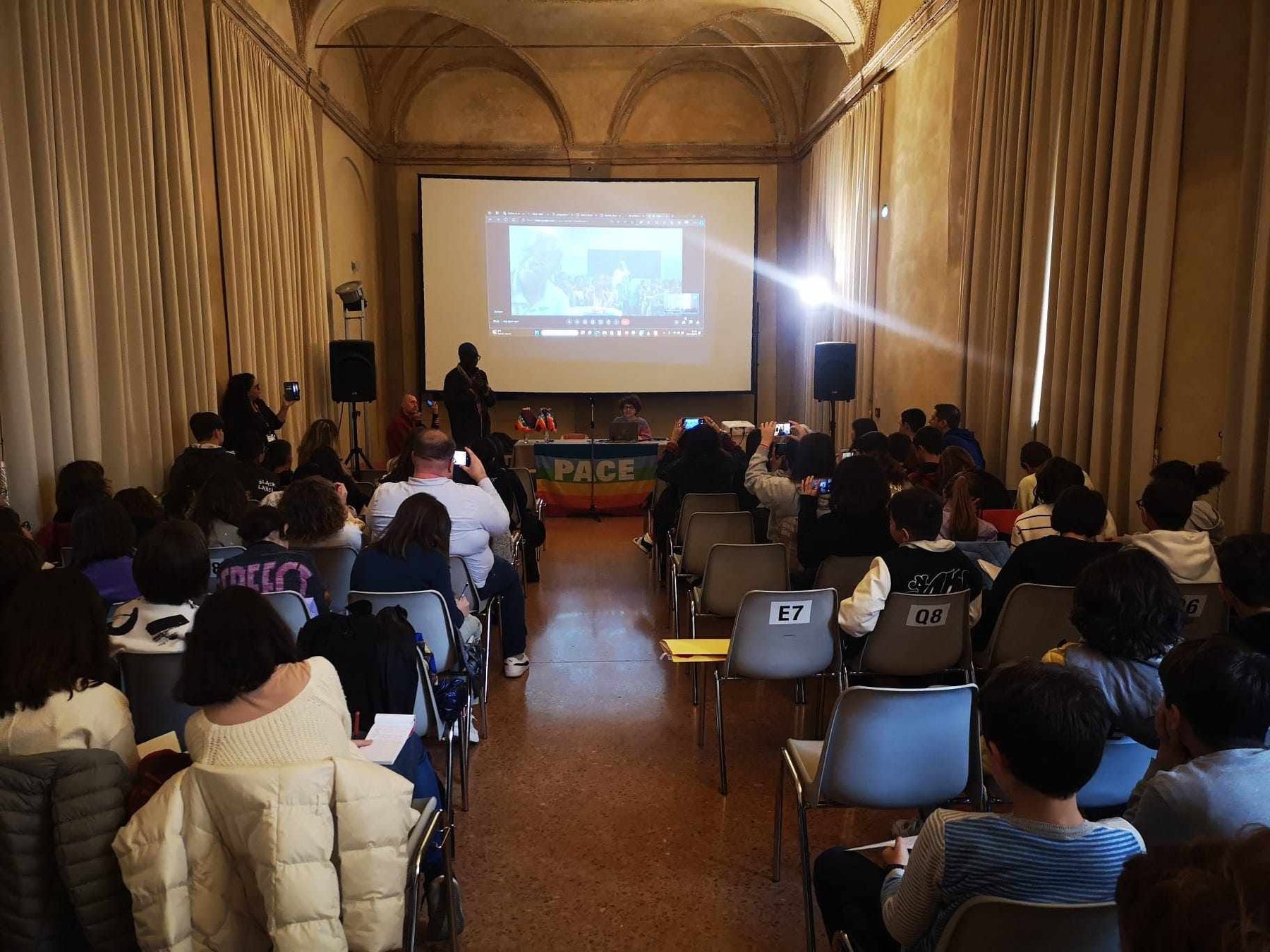 Studenti visti di spalle nella Sala dell'Antico Portico durante il collegamento internazionale di Diritti in viaggio