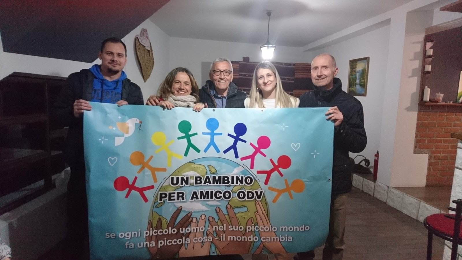 Volontari e partner in Serbia tengono lo striscione di Un bambino per amico